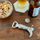 Cowboy boot bottle opener on a wooden surface with cashews, a bottle, and a cap.