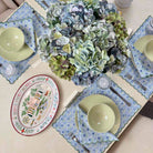 Dining table setting with floral plates, bowls, and a centerpiece of hydrangeas.
