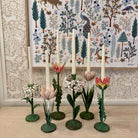 Decorative candle holders with floral designs on a wooden surface, with a patterned wall in the background.