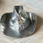 Silver cowboy hat-shaped object on a wooden surface