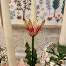 Decorative candle holder with floral design in front of a floral-patterned wall.