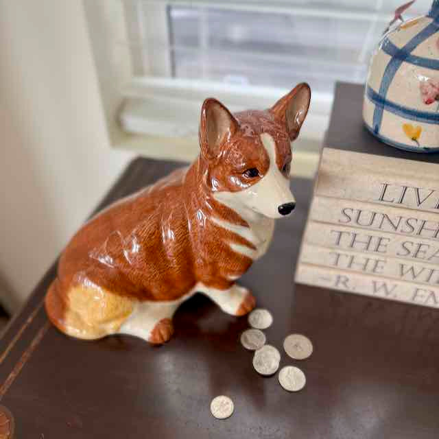 Dog-shaped piggy bank with coins on a surface