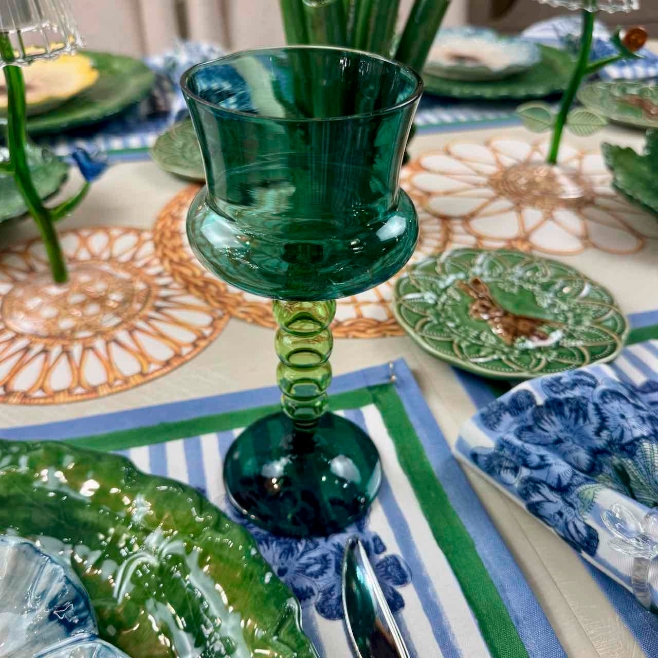 Green glass goblet on a decorative table setting with plates and placemats.