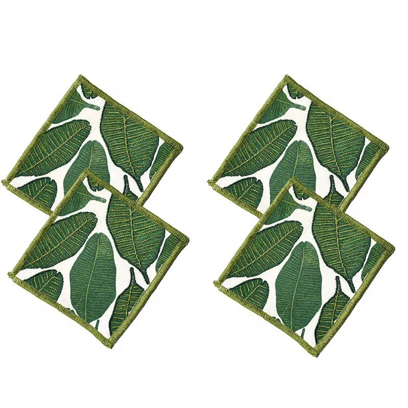 Two green leaf-patterned coasters on a white background