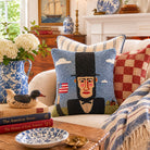 Decorative pillows on a couch with a floral arrangement and books in a living room setting.