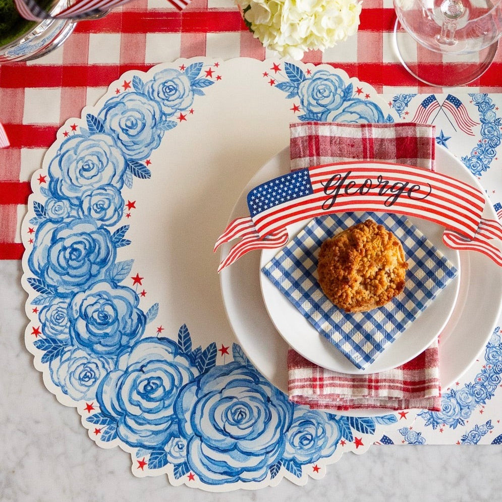 Table setting with decorative placemats, napkins, and a cookie on a checkered tablecloth.