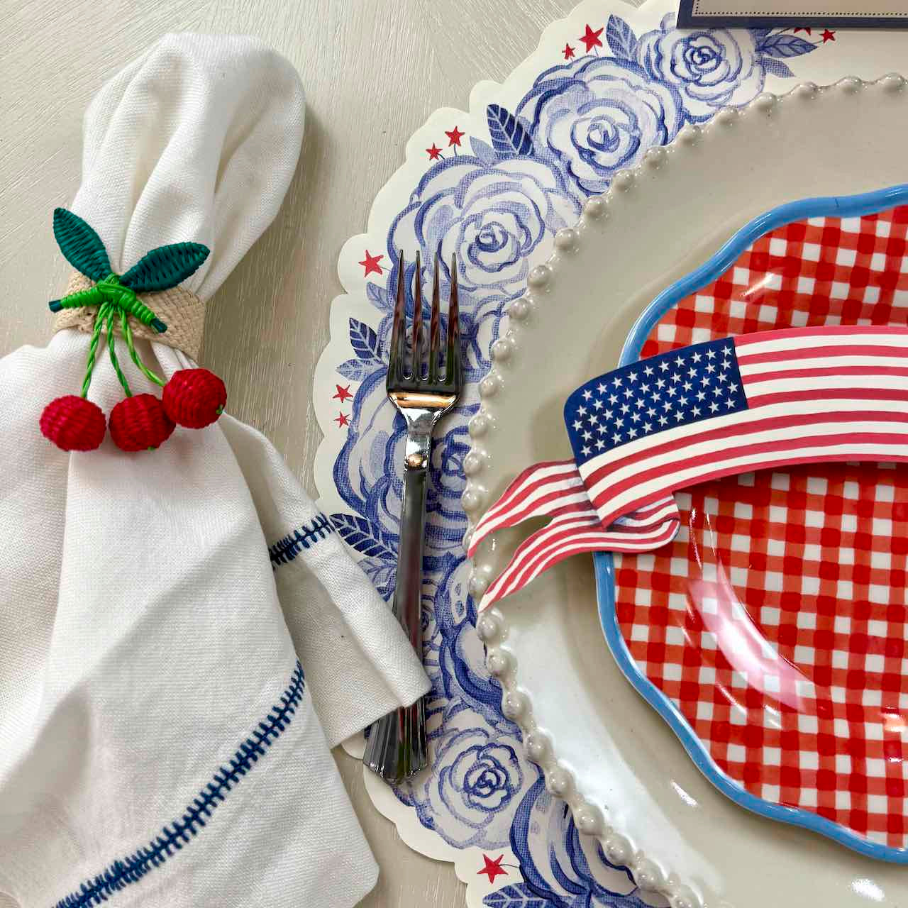 Dinner setting with American flag-themed plate, napkin, and cutlery on a table.
