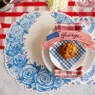 Table setting with decorative placemats, napkins, and a cookie on a checkered tablecloth.