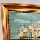 Framed painting of a ship with American flag on a textured wall