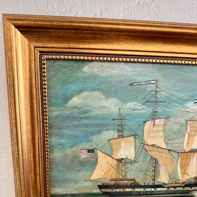 Framed painting of a ship with American flag on a textured wall