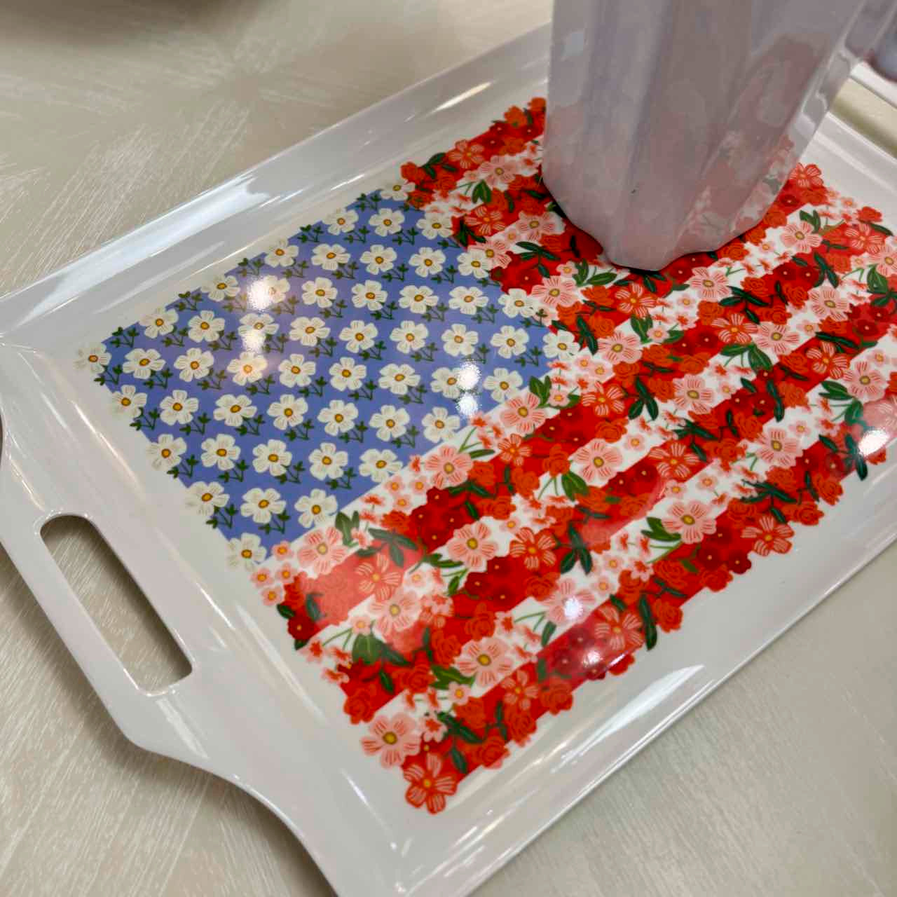 Floral-patterned tray with a white handle on a light surface