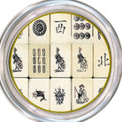 A circular silver metal tin containing 12 ivory-colored mahjong tiles with black printed symbols and characters, arranged in a 3x4 grid.