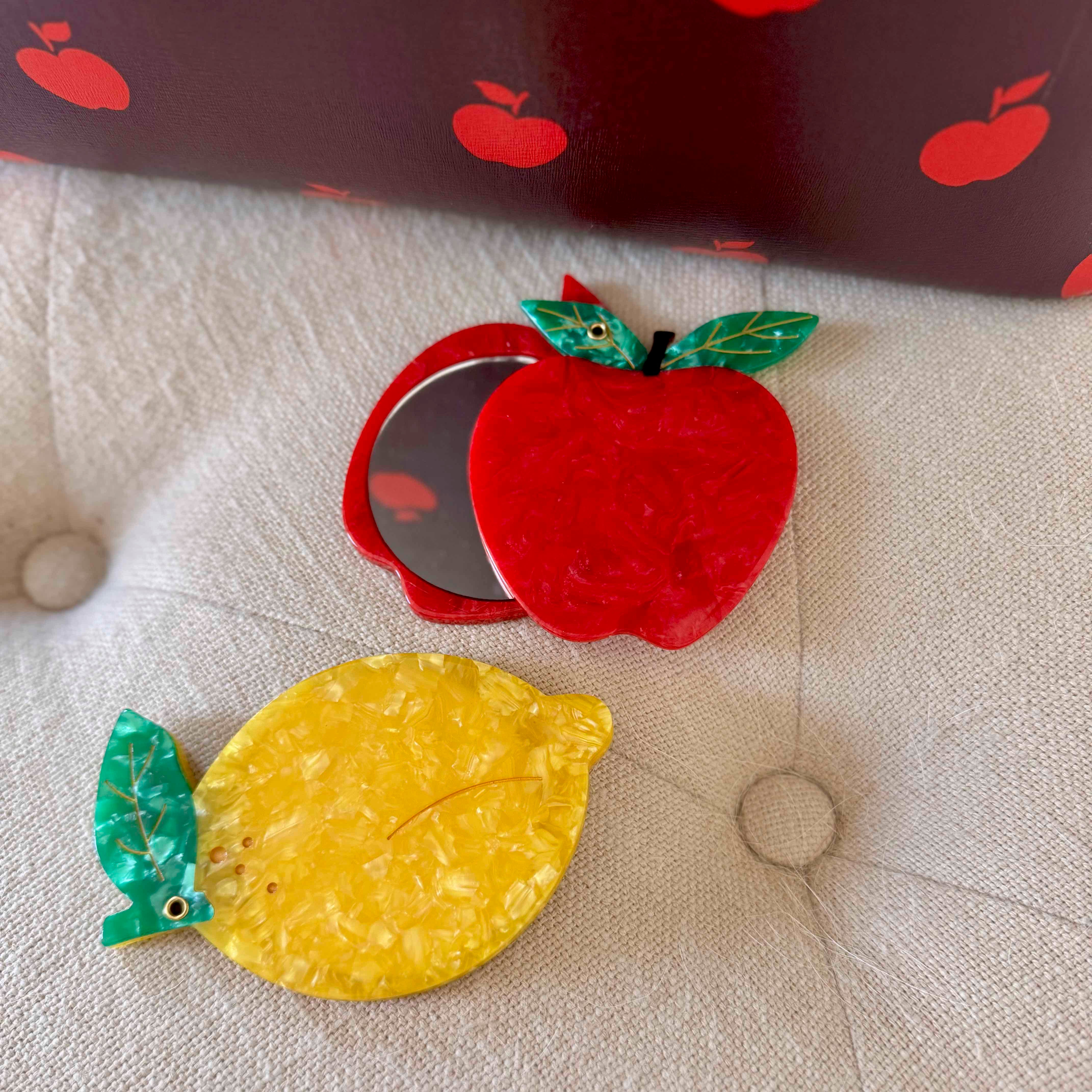 Red apple and yellow lemon decorative items on a textured surface with red apple patterned background.
