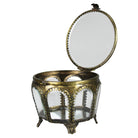 An ornate round jewelry box with an open lid, featuring a gold-toned metal frame, clear glass panels, and a small mirror on the inside of the lid, set against a plain white background.