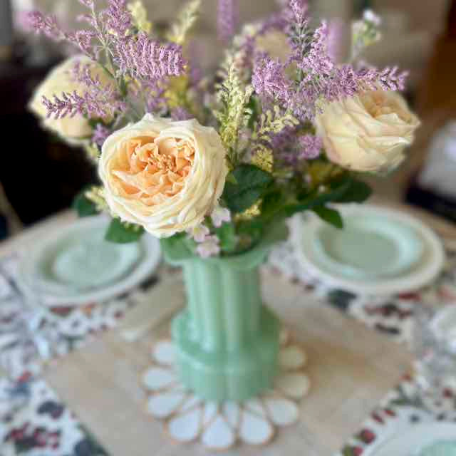 Floral arrangement in a green vase on a decorative tablecloth