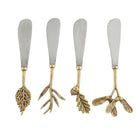 Four decorative spreader knives with silver-toned metal blades and ornate gold-toned handles shaped like leaves, branches, acorns, and birds, shown on a plain white background.