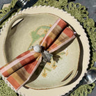 Napkin ring with a striped napkin on a ceramic plate with floral design