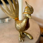 Gold dragon candle holder with a white candle inside on a wooden surface.