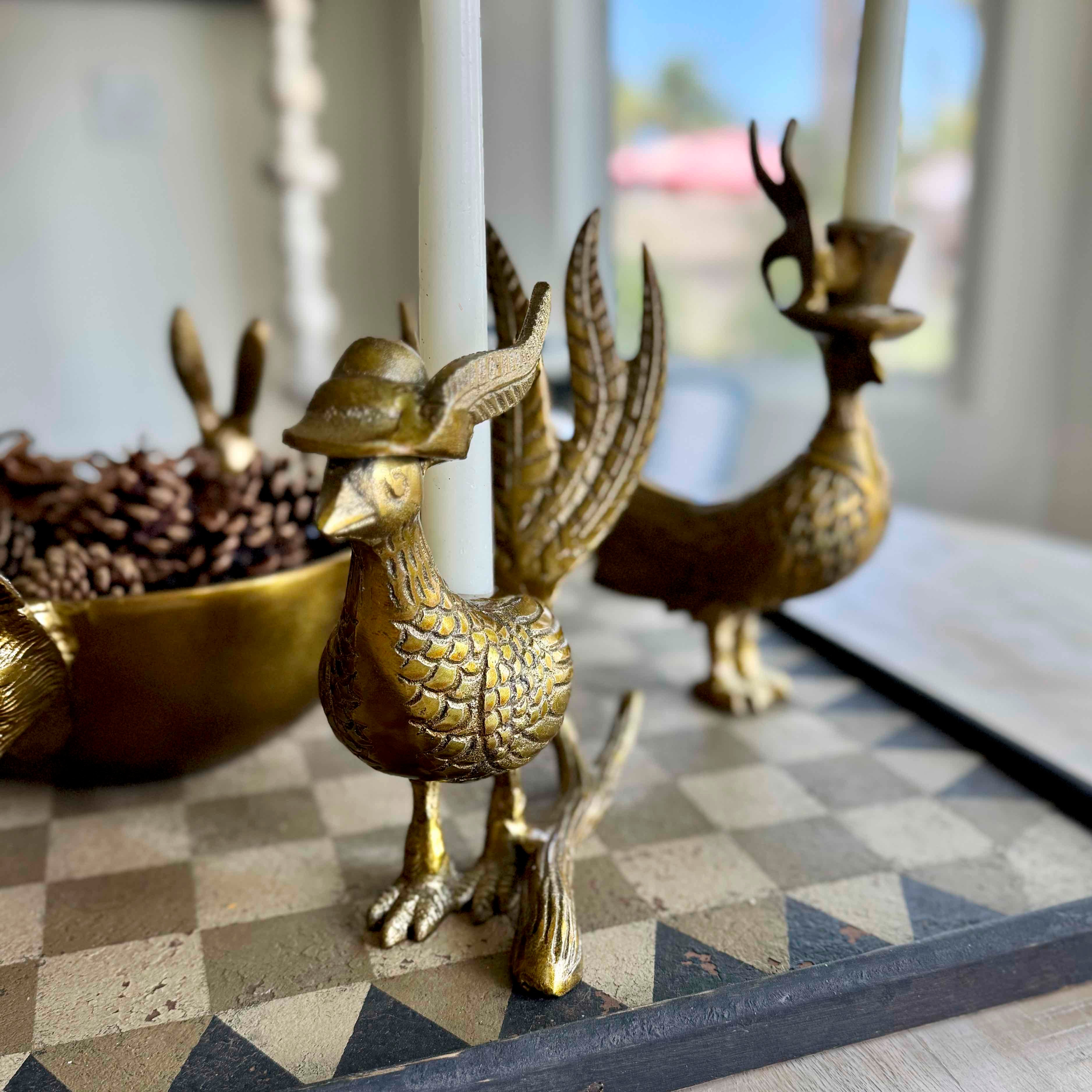 Brass bird and deer figurines on a checkered surface with a blurred background