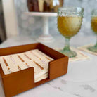 Wooden coaster set with cards in a holder on a marble surface.
