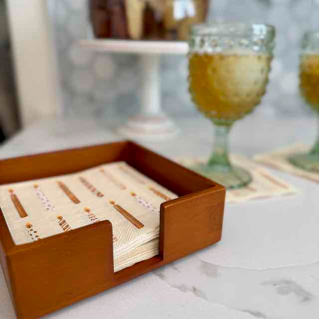 Wooden coaster set with cards in a holder on a marble surface.
