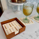 Set of business cards in a wooden holder on a marble surface with glasses of juice in the background.