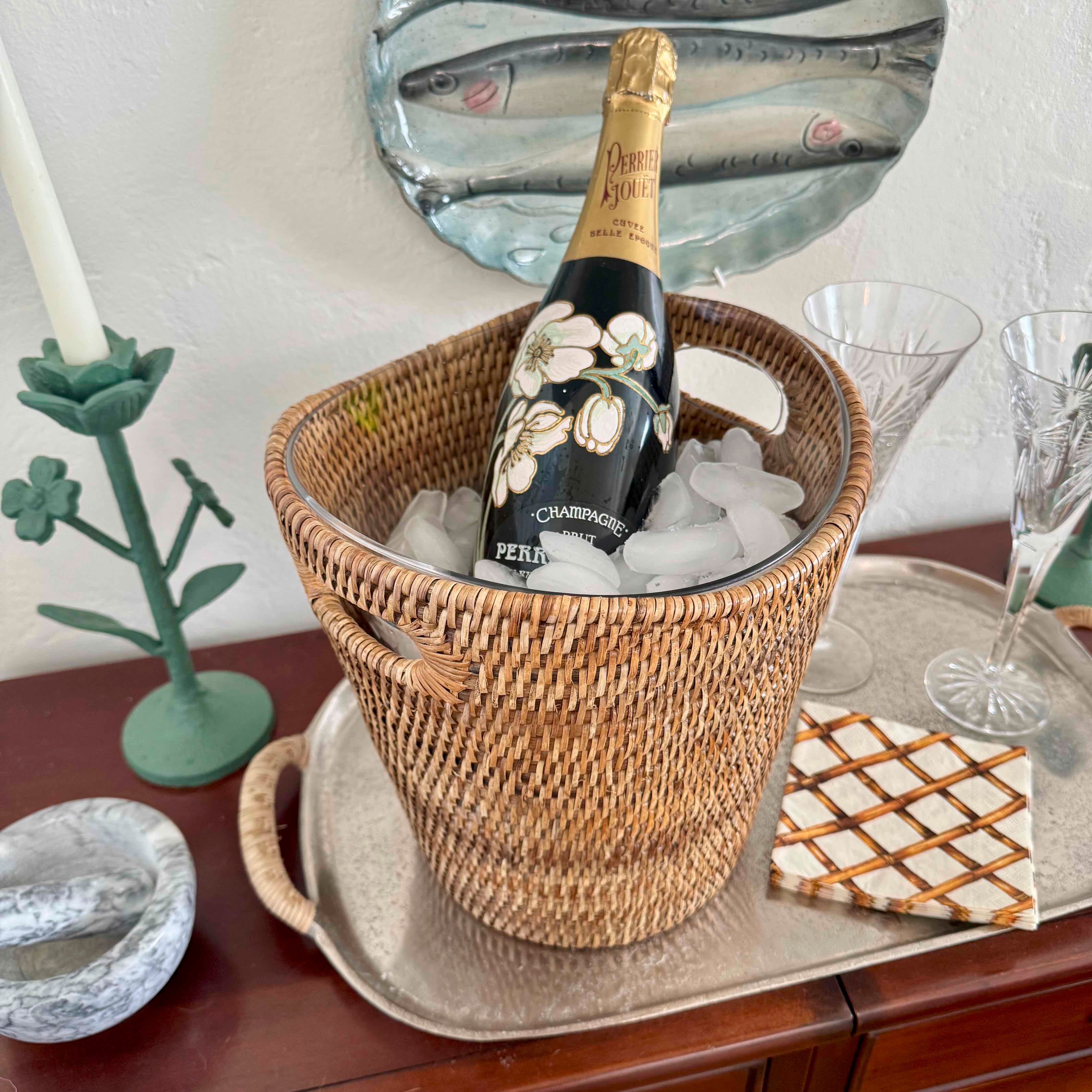 Bottle of champagne in an ice bucket on a table with glasses and decor.