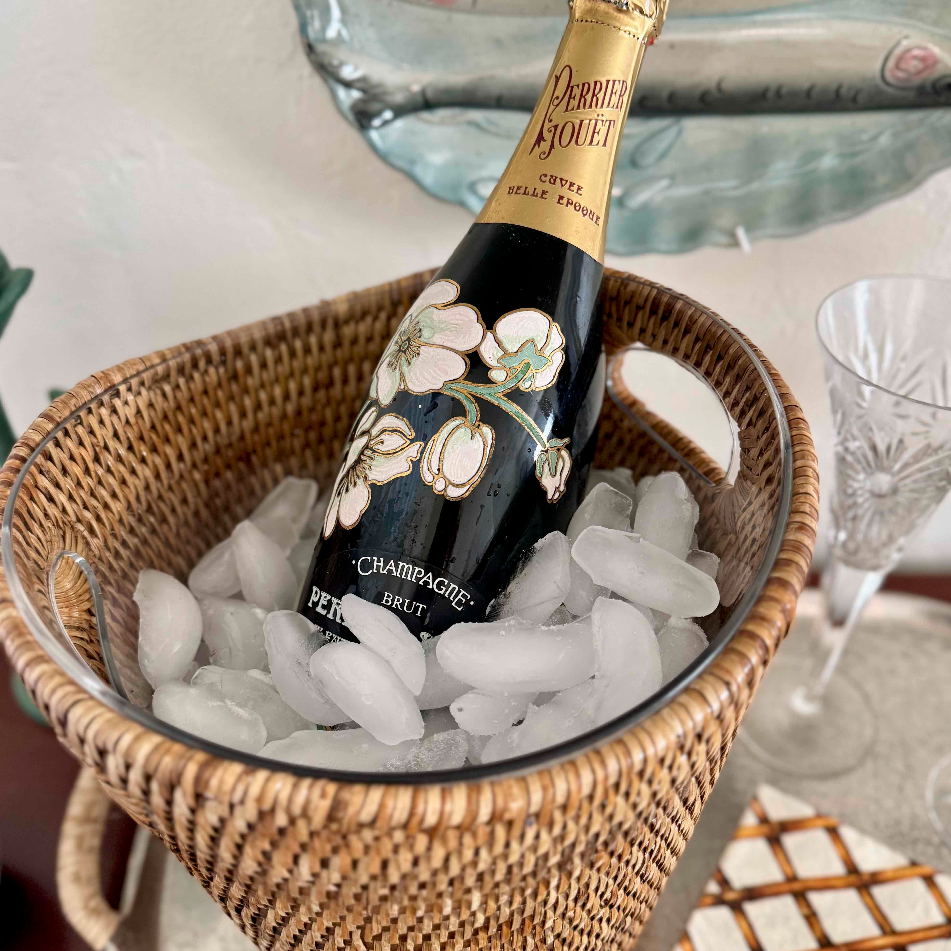 Perrier-Joué champagne bottle in a basket of ice with glasses in the background