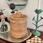 Woven basket with a lid on a table next to decorative items