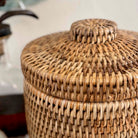Woven rattan storage basket with a lid on a blurred background