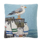 A square hand-tufted decorative pillow featuring a seagull standing on a dock with sailboats against a light blue background.