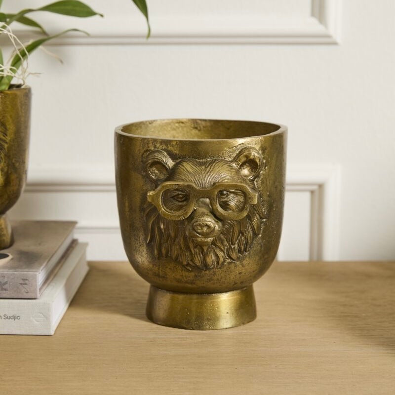 Bronze bear-shaped container with glasses on a wooden surface