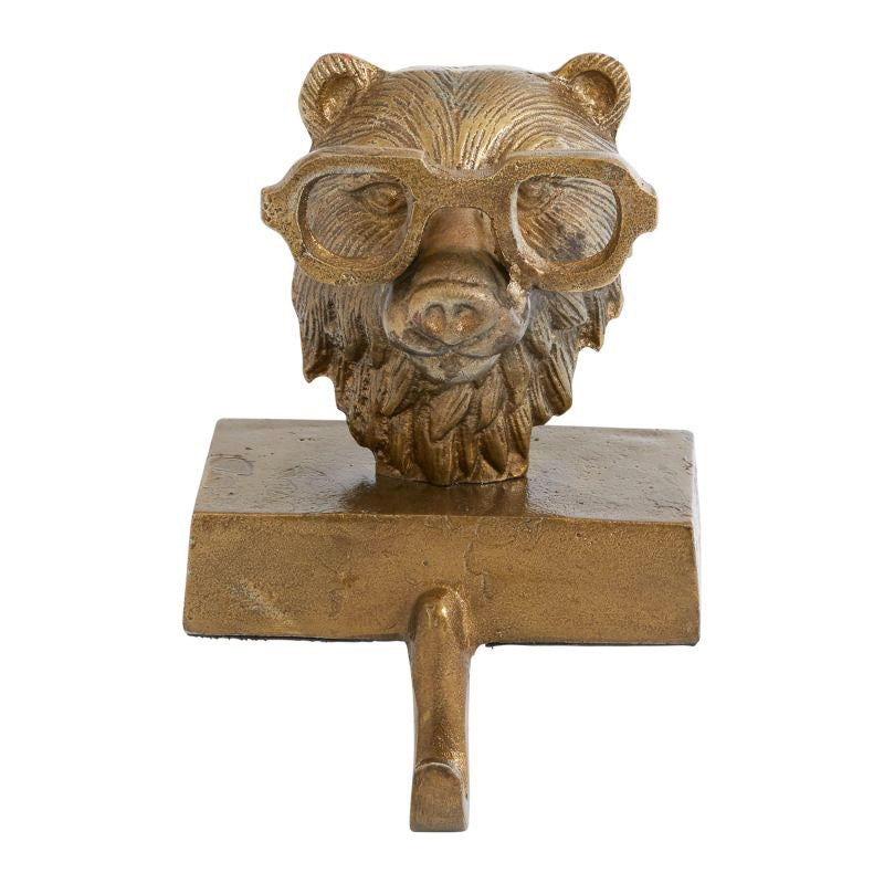 A metal stocking holder in the shape of a bear wearing glasses, with a gold antique finish.