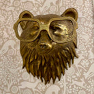 Bronze bear head wall decoration with glasses on a floral-patterned background