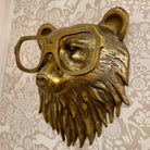 Bronze bear head sculpture wearing glasses on a decorative wall background