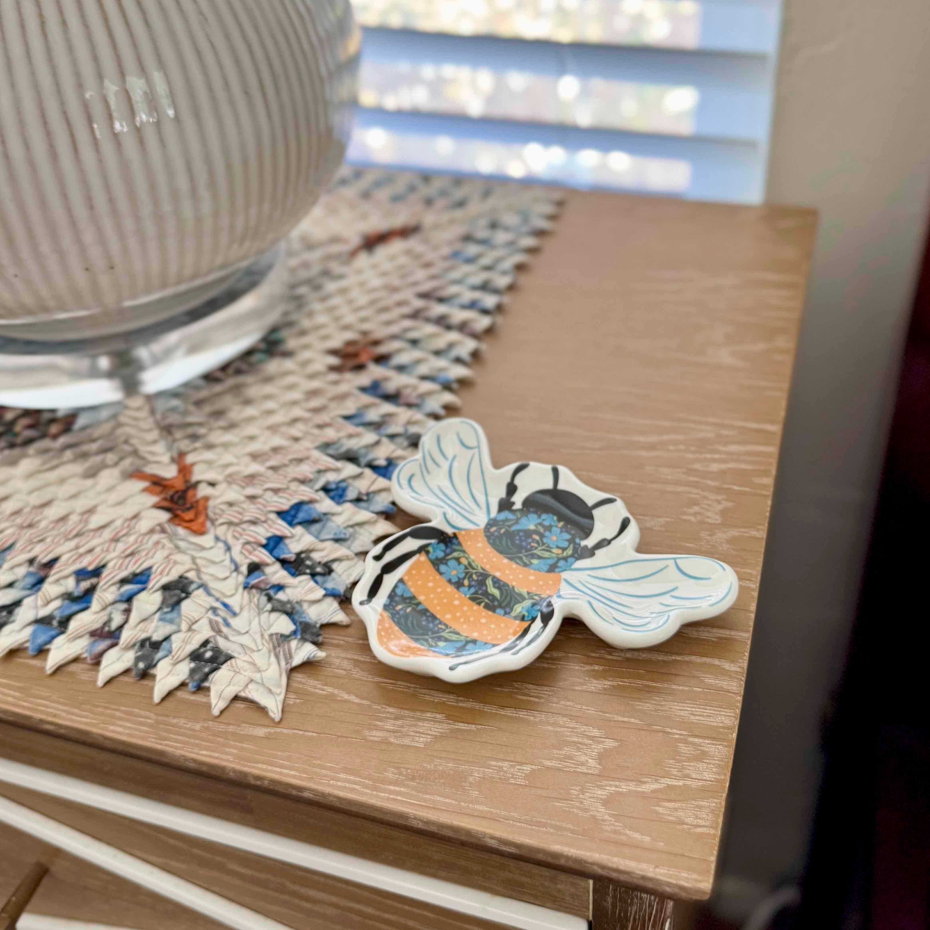 Decorative bee-shaped object with floral patterns on a wooden surface