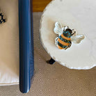 Decorative bee sticker on a white surface with a blue object next to it.