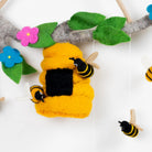 Toy bee hive with bees and flowers on a branch against a white background