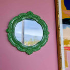 Green decorative mirror on a pink wall