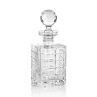 A clear crystal brandy decanter with a rounded top and a long, slender body. It features intricate cut patterns on its surface.
