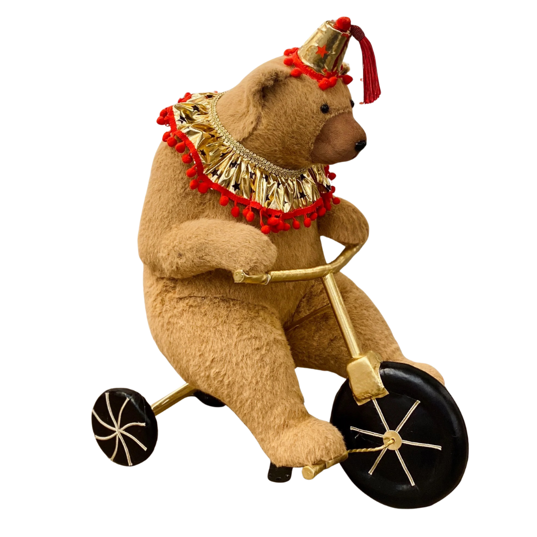 Teddy bear riding a tricycle with festive decorations on a white background