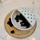 White ceramic colander with blackberries on a wooden board