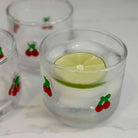 Clear glass with lime wedge and ice cubes on a white background