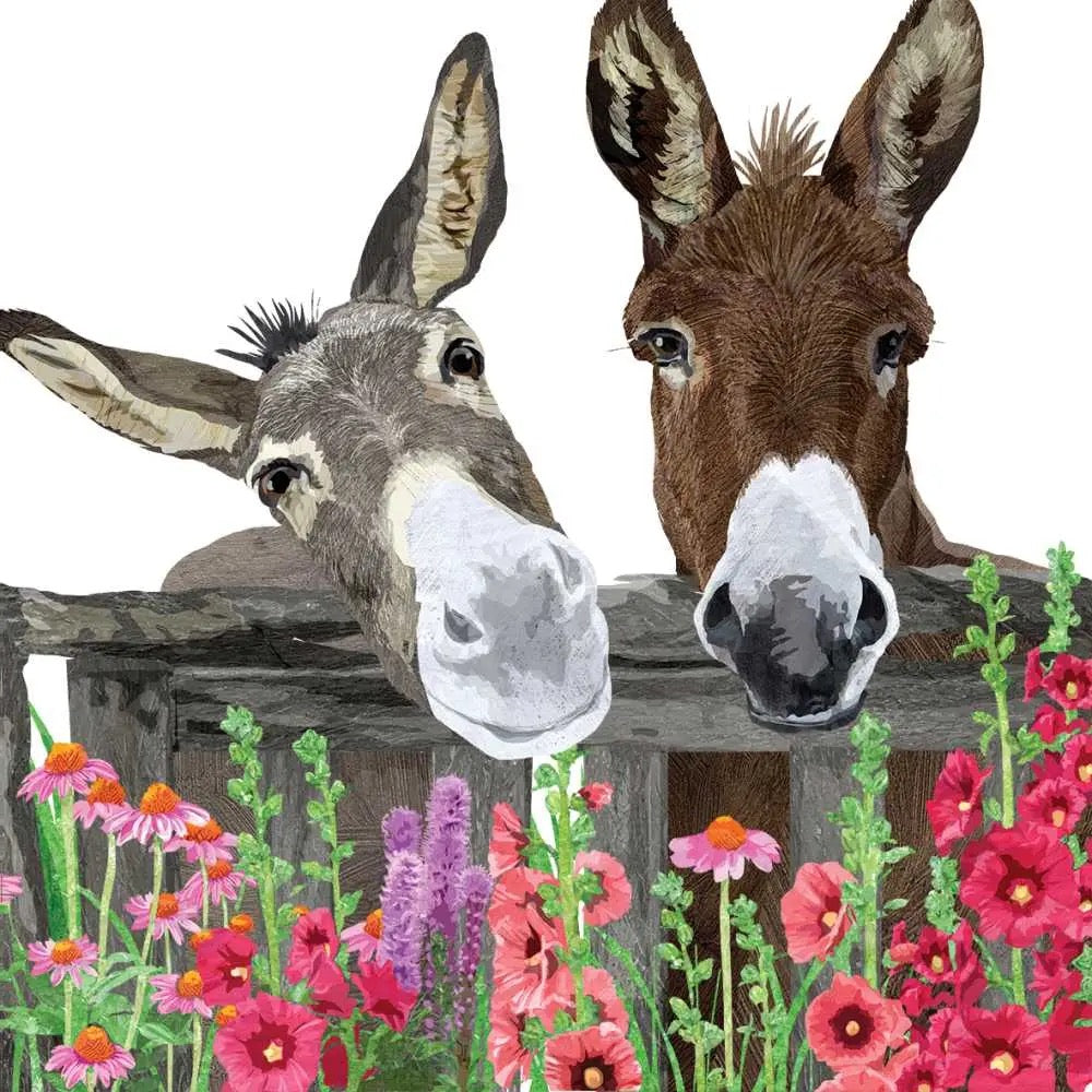 Two donkeys peering over a wooden fence with colorful flowers in the foreground.