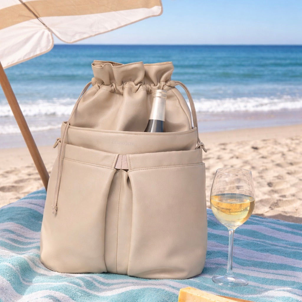 Beige cooler bag with a bottle of wine and a glass on a beach.