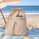 Beige cooler bag with a bottle of wine and a glass on a beach.