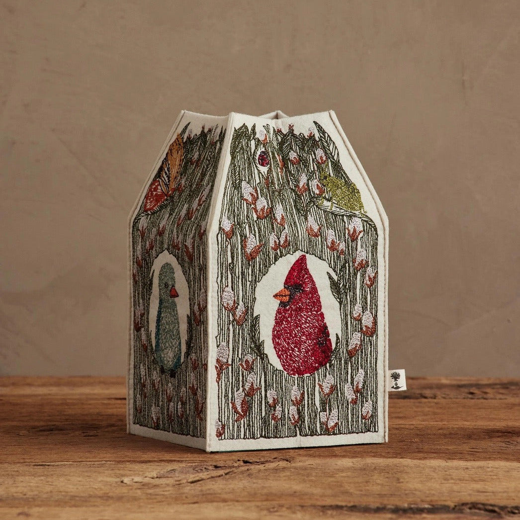 Decorative birdhouse with a red cardinal design on a wooden surface and brown background