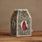 Decorative birdhouse with a red cardinal design on a wooden surface and brown background