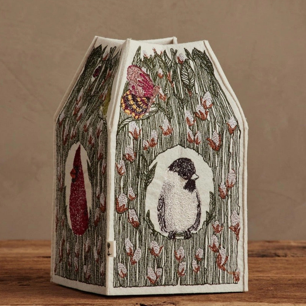 Decorative birdhouse with illustrations on a wooden surface and brown background