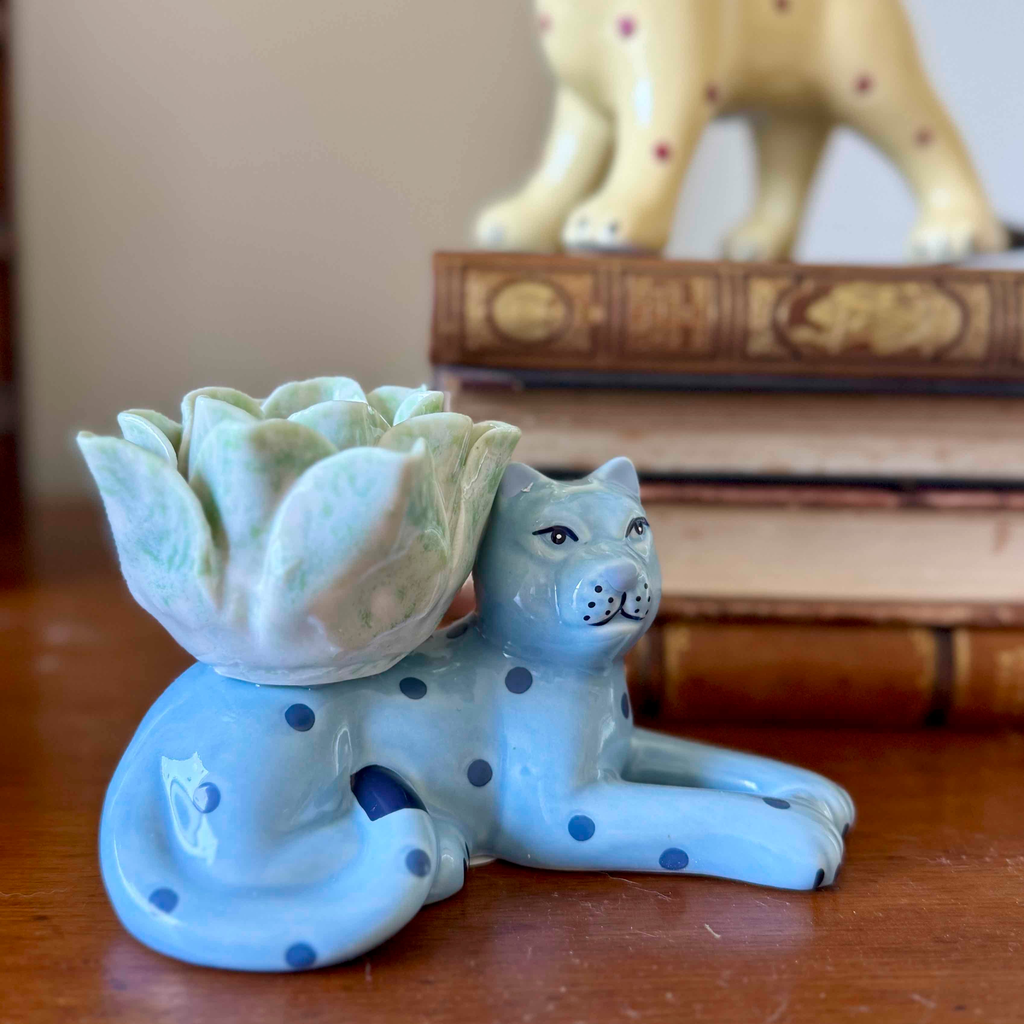Ceramic cat figurine with a lotus flower on a wooden surface